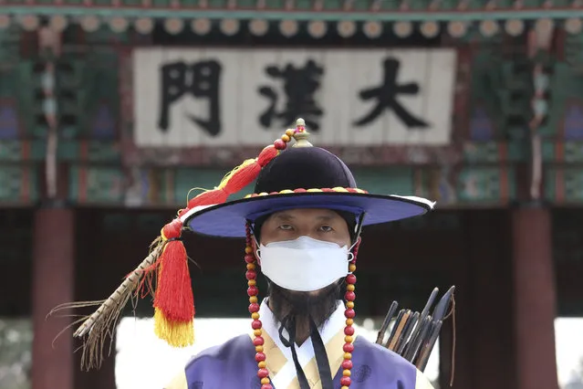 A South Korean Imperial guard wears a mask during a reenactment of the Royal Guards Changing Ceremony in front of Deoksu Palace in Seoul, South Korea, Thursday, January 30, 2020. The death toll rose to 170 in the new virus outbreak in China on Thursday as foreign evacuees from the worst-hit region begin returning home under close observation and world health officials expressed “great concern” that the disease is starting to spread between people outside of China. The sign reads “Daehanmun Gate”. (Photo by Ahn Young-joon/AP Photo)