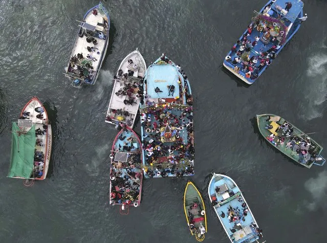 Fishermen follow a statue of Saint Peter being carried on a boat, center, as part of his feast day procession on the Pacific Ocean in honor of the Catholic patron Saint of fishermen in Pucusana, Peru, Wednesday, June 29, 2022. (Photo by Martin Mejia/AP Photo)