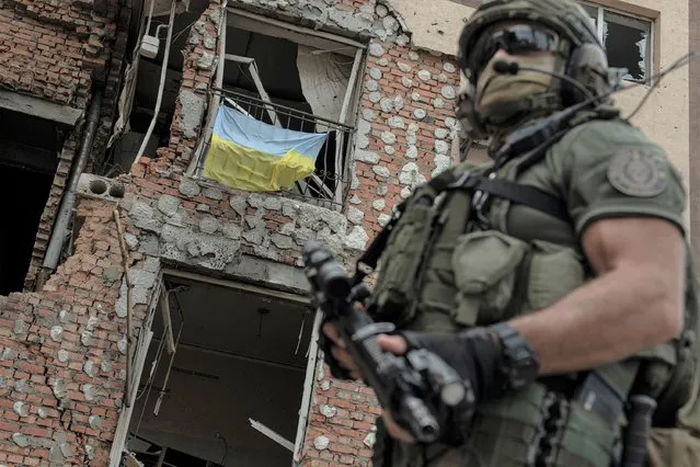 A Ukrainian serviceman is backdropped by a destroyed building in Irpin, Ukraine, Monday, July 11, 2022. (Photo by Andrew Kravchenko/AP Photo)