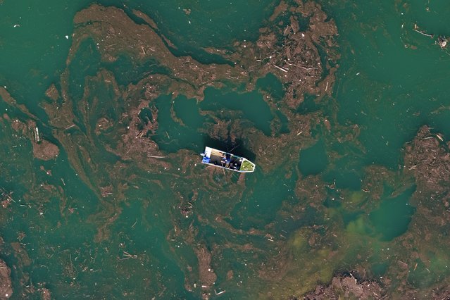 Aerial view of Ibro Mesic rowing his boat through mud and waste after devastating floods and landslides put tons of waste in Jablanicko lake near Ostrozac, Bosnia, Sunday, October 20, 2024. (Photo by Armin Durgut/AP Photo)