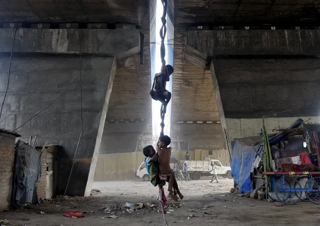 Children play on an improvised swing made of used bicycle tyres and cloth suspended from a flyover in Kolkata April 23, 2015. (Photo by Rupak De Chowdhuri/Reuters)