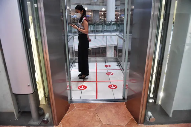 A woman stands in an elevator with markers on the floor for social distancing measures in a shopping mall amid concerns over the spread of the COVID-19 coronavirus in Bangkok on March 20, 2020. (Photo by Lillian Suwanrumpha/AFP Photo)