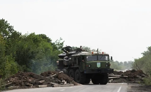 A Ukrainian serviceman gestures on a tank, as it is towed away by a military truck near Bakhmut, as Russia's invasion of Ukraine continues, in Donetsk region, Ukraine on August 15, 2022. (Photo by Nacho Doce/Reuters)
