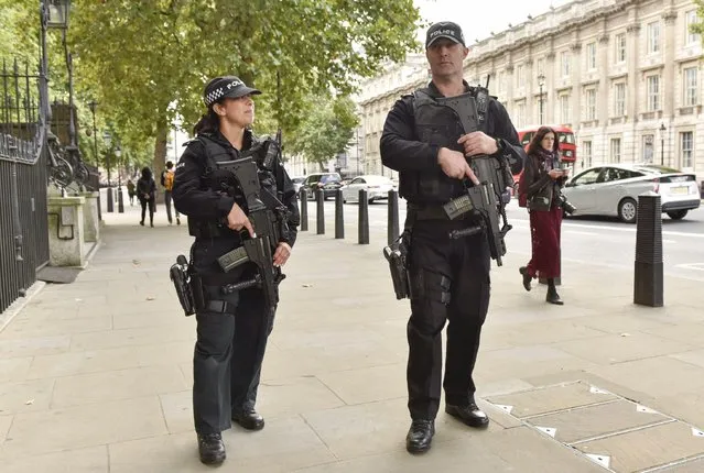 Armed police officers walk on a street after terror attack in London, England on September 17, 2017. British Home Secretary Amber Rudd said on Sunday that the United Kingdom's terrorism threat level has been lowered from “critical” to “severe” after being raised to the highest possible in the wake of the Friday explosion at a subway station in west London. (Photo by Xinhua News Agency/Rex Features/Shutterstock)