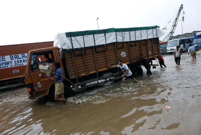 People push a stranded truck in a waterlogged highway after heavy rains in Gurugram, previously known as Gurgaon, on the outskirts of New Delhi, India, July 29, 2016. (Photo by Adnan Abidi/Reuters)