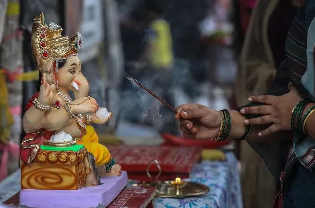 Indian devotee offers prayer to an idol of the elephant-headed Hindu God Ganesha, before taking it to their home on the occasion of Ganesh Chaturthi, in Mumbai, India, 31 August 2022. (Photo by Divyakant Solanki/EPA/EFE)