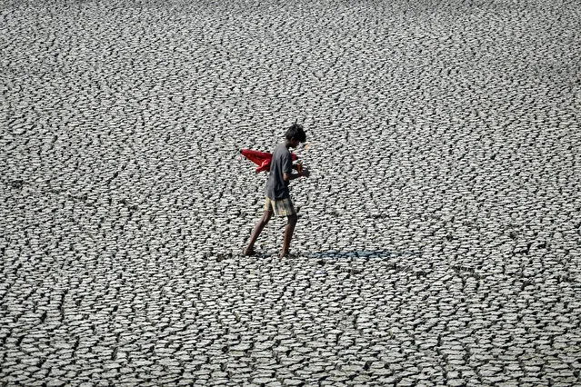 A youth walks on the parched bed of a temple tank during a hot day in Chennai on April 24, 2020. (Photo by Arun Sankar/AFP Photo)