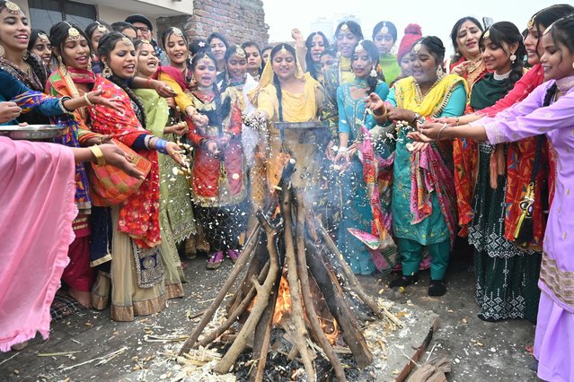 Girls throw puffed rice, sweets, and ground nuts in a bonfire ahead of the upcoming “Lohri” festival, in Amritsar on January 10, 2025. (Photo by Narinder Nanu/AFP Photo)