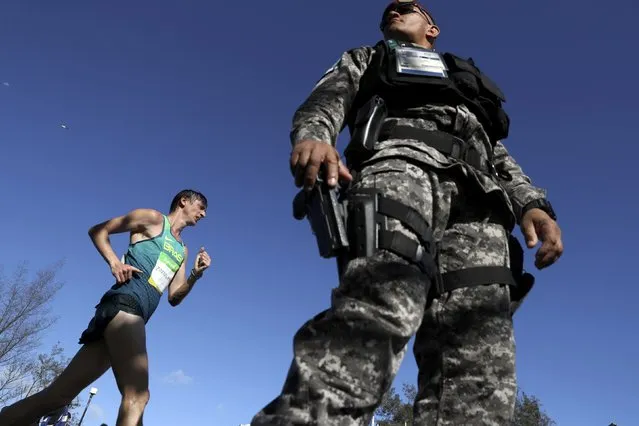 2016 Rio Olympics, Athletics, Final, Men's 20km Race Walk, Pontal, Rio de Janeiro, Brazil on August 12, 2016. Moacir Zimmermann (BRA) of Brazil walks past a soldier on security duty. (Photo by Damir Sagolj/Reuters)