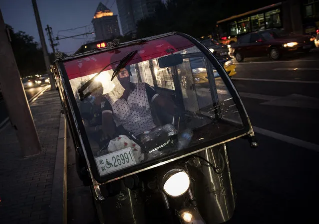 A Chinese auto-rickshaw driver drops off a female passenger in the trendy Sanlitun neighborhood on September 5, 2014 in Beijing, China. (Photo by Kevin Frayer/Getty Images)