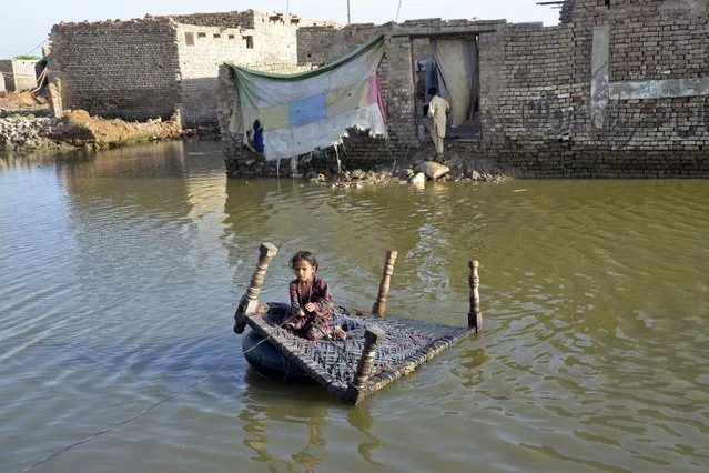 A girl sits on a cot as she crosses a flooded street at Sohbatpur in Jaffarabad district of Balochistan province on October 4, 2022. (Photo by Fida Hussain/AFP Photo)
