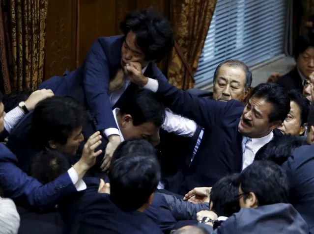 Lawmakers crowd around Yoshitada Konoike, chairman of the upper house special committee on security, as Masahisa Sato (R) of Japan's ruling Liberal Democratic Party's fist lands on opposition Democratic Party of Japan lawmaker Hiroyuki Konishi (top) during a vote at an upper house special committee session on security-related legislation at the parliament in Tokyo, Japan, September 17, 2015. (Photo by Toru Hanai/Reuters)