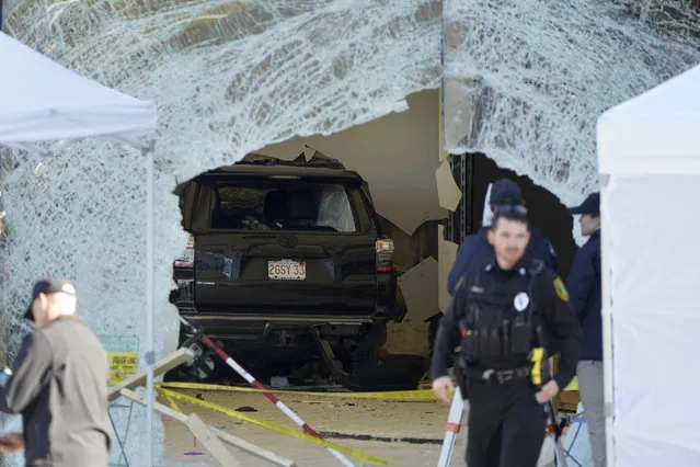 An SUV rests inside an Apple store behind a large hole in the glass front of the store, Monday, November 21, 2022, in Hingham, Mass. One person was killed and 16 others were injured Monday when the SUV crashed into the store, authorities said. (Photo by Steven Senne/AP Photo)
