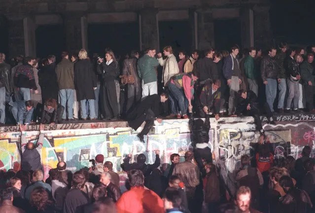 West Berlin citizens continue their vigil atop the Berlin Wall in front of the Brandenburg Gate, November 10, 1989. (Photo by Andree Kaiser/Reuters)