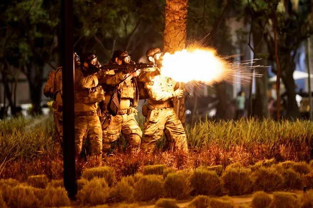 A police officer fires a shotgun as supporters of Brazil's President Jair Bolsonaro protest after supreme court justice Alexandre de Moraes ordered a temporary arrest warrant of indigenous leader Jose Acacio Serere Xavante for alleged anti-democratic acts, in Brasilia, Brazil on December 12, 2022. (Photo by Ueslei Marcelino/Reuters)