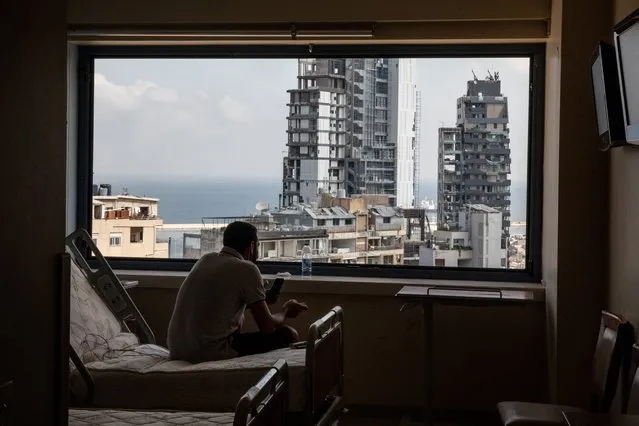 The Beirut port is seen through a smashed window as a man takes a break from cleaning debris from the heavily damaged St George Hospital on August 13, 2020 in Beirut, Lebanon. The explosion at Beirut's port last week killed over 200 people, injured thousands, and upended countless lives. There has been little visible support from government agencies to help residents clear debris and help the displaced, although scores of volunteers from around Lebanon have descended on the city to help clean. (Photo by Chris McGrath/Getty Images)