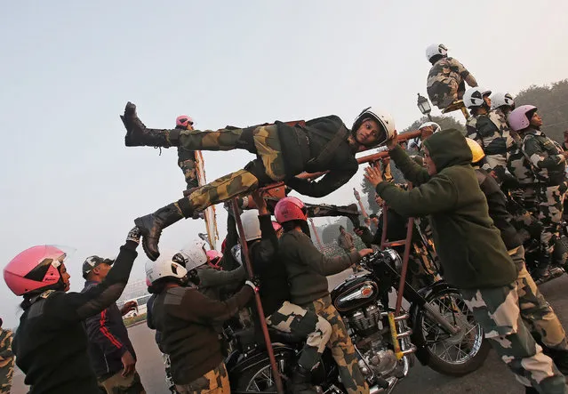 India's Border Security Force (BSF) “Daredevils” women motorcycle riders help their colleague to balance on a bike during a rehearsal for the Republic Day parade on a cold winter morning in New Delhi, India, January 10, 2018. (Photo by Adnan Abidi/Reuters)