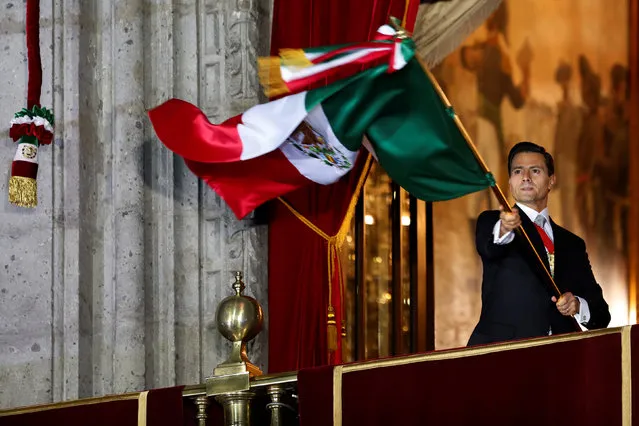 Mexico's President Enrique Pena Nieto waves the national flag after he shouted the “Cry of Independence” as Mexico marks the 206th anniversary of the day rebel priest Manuel Hidalgo set it on the path to independence in Mexico City, Mexico September 16, 2016. (Photo by Carlos Jasso/Reuters)