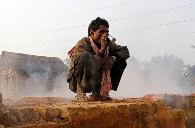 A labourer drinks tea inside a brick factory on a cold winter morning on the outskirts of Agartala, January 10, 2018. (Photo by Jayanta Dey/Reuters)