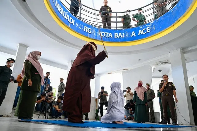 A woman is caned by a sharia policeman as a punishment for being caught in close proximity with a man in Banda Aceh on December 21, 2022. (Photo by Chaideer Mahyuddin/AFP Photo)
