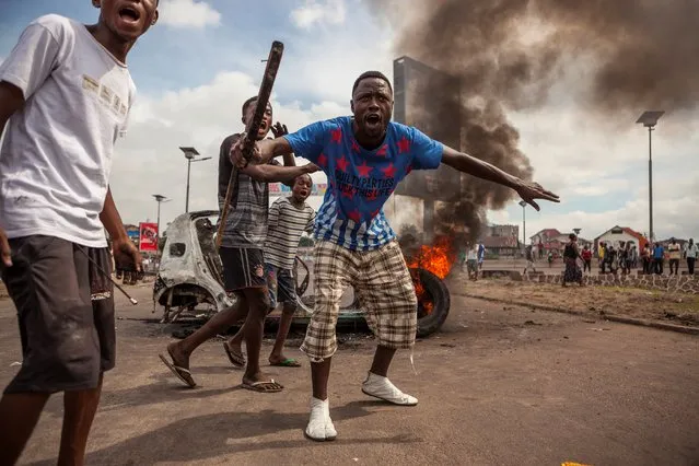 Demonstrators gather in front of a burning car during an opposition rally in Kinshasa on September 19, 2016. Police fired tear gas at scores of opposition supporters rallying in Kinshasa to demand that DR Congo's long-serving President Joseph Kabila step down this year, AFP journalists said. Kabila, who has ruled DR Congo since 2001, is banned under the constitution from running again – but he has given no sign of intending to give up his job in December. (Photo by Eduardo Soteras/AFP Photo)