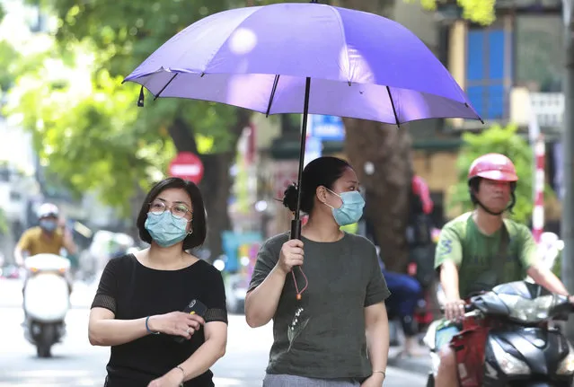 Women wearing face masks walk on the street in Hanoi, Vietnam, Thursday, July 30, 2020. Vietnam on Thursday reported several more cases of COVID-19, as the first outbreak in over three months spread to cities while authorities say they cannot trace its source. (Photo by Hau Dinh/AP Photo)