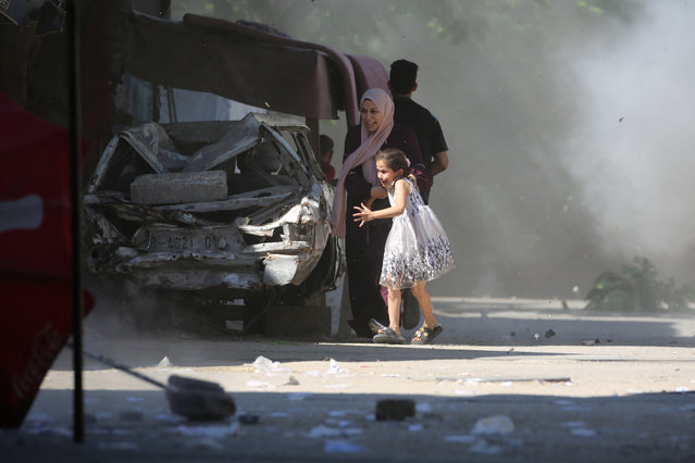 A Palestinian mother and her daughter rush for cover during an Israeli strike in the Al-Bureij camp in the central Gaza Strip on July 4, 2025. (Photo by Eyad Baba/AFP Photo)