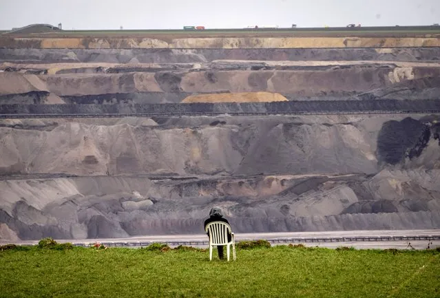 A person sits in a chair next to the Garzweiler lignite opencast mine at the Luetzerath village near Erkelenz, Germany, Tuesday, January 10, 2023.  Environmental activists were locked in a standoff with police this week around the hamlet of Luetzerath that's due to be bulldozed for the expansion of a nearby lignite mine. (Photo by Michael Probst/AP Photo)