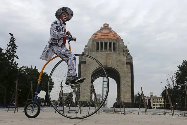 A clown rides his bicycle at the Monument to the Revolution as he takes part in the Latin American Clown Convention in Mexico City, Mexico, October 21, 2015. (Photo by Henry Romero/Reuters)
