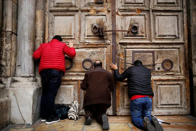 Worshippers kneel and pray in front of the closed doors of the Church of the Holy Sepulchre in Jerusalem's Old City, February 25, 2018. Christian leaders took the rare step of closing the Church of the Holy Sepulchre, built at the site of Jesus's burial in Jerusalem, in protest at Israeli tax measures and a proposed property law. (Photo by Amir Cohen/Reuters)