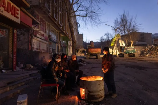 People gather around a fire for warmth as they wait for search and rescue teams to find their missing relatives, following the deadly earthquake in Kahramanmaras, Turkey on February 16, 2023. (Photo by Eloisa Lopez/Reuters)