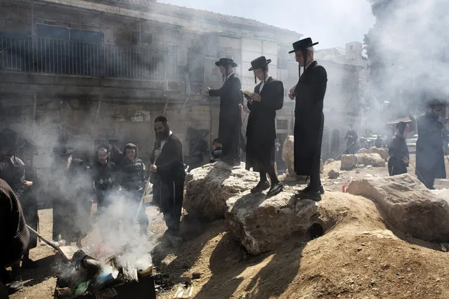 Ultra-Orthodox Jews pray as they burn leavened items in a final preparation before the start at sundown of the Jewish Pesach (Passover) holiday, on March 25, 2013 in Jerusalem. Religious Jews worldwide eat matzoth during the eight-day Pesach holiday that commemorates the Israelis' exodus from Egypt some 3,500 years ago and their ancestors' plight by refraining from eating leavened food products. (Photo by Menahem Kahana/AFP Photo)