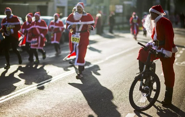A man dressed as Father Christmas rides a bicycle during the Nikolaus Lauf (Santa Claus Run) in the east German town of Michendorf, southwest of Berlin December 7, 2014. (Photo by Hannibal Hanschke/Reuters)