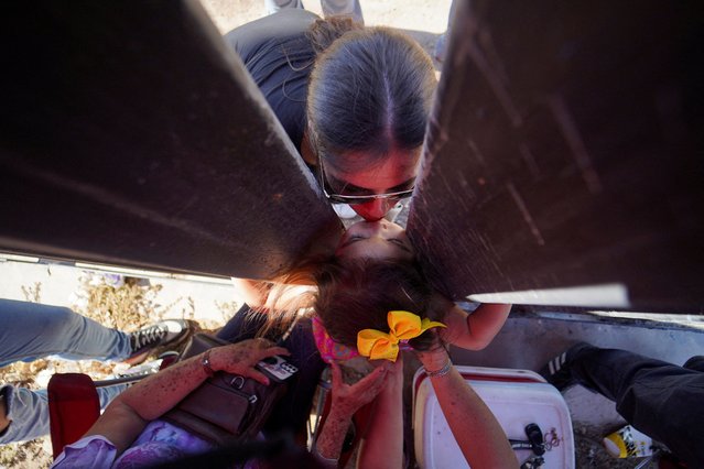 A member of the Orduno Castro family, who lives in North Carolina and can't cross into Mexico, kisses her niece during a family meeting at the border fence that separates Mexico and the U.S., ahead of Mother's Day, as seen from Mexicali, Mexico, on May 6, 2024. (Photo by Victor Medina/Reuters)