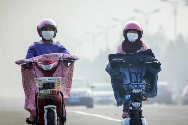 People wearing masks ride along a street on a hazy day in Lianyungang, Jiangsu province, October 23, 2015. (Photo by Reuters/Stringer)