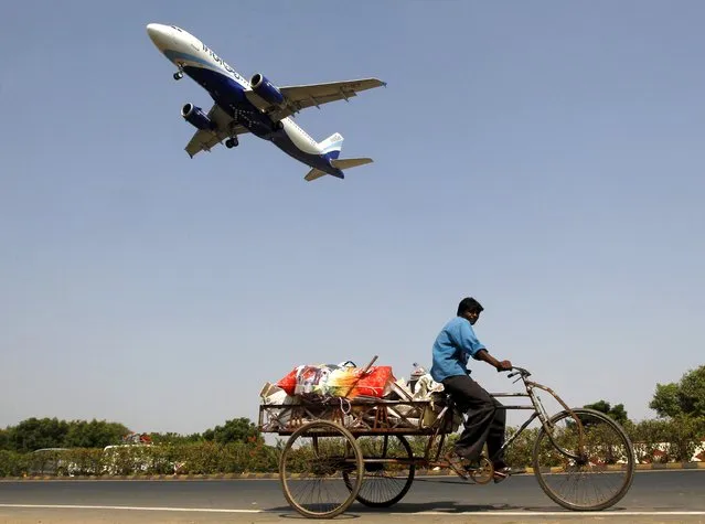 An IndiGo Airlines aircraft prepares to land as a man paddles his cycle rickshaw in Ahmedabad, India, October 26, 2015.  Indian budget airline IndiGo is likely to reap the rewards of its frugal business strategy when it launches on Tuesday an up to $465 million initial public offer in one of the world's fastest growing – and most competitive – aviation markets. (Photo by Amit Dave/Reuters)