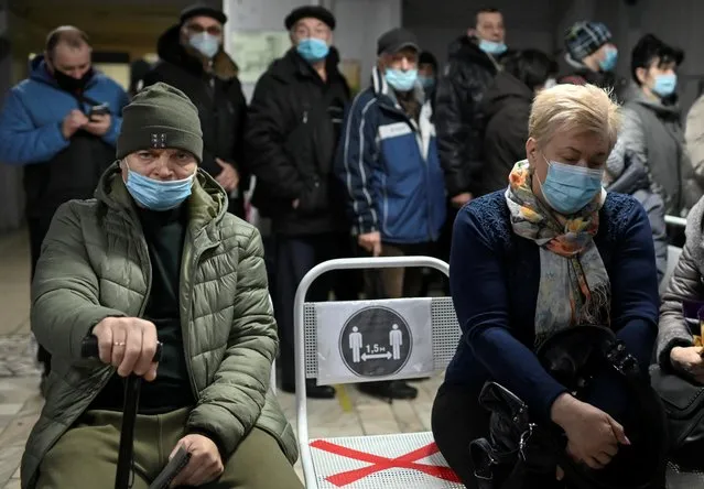 People wearing protective face masks, used as a preventive measure against the spread of the coronavirus disease (COVID-19), wait in a queue near a reception desk at a local clinic in Omsk, Russia on November 9, 2020. (Photo by Alexey Malgavko/Reuters)
