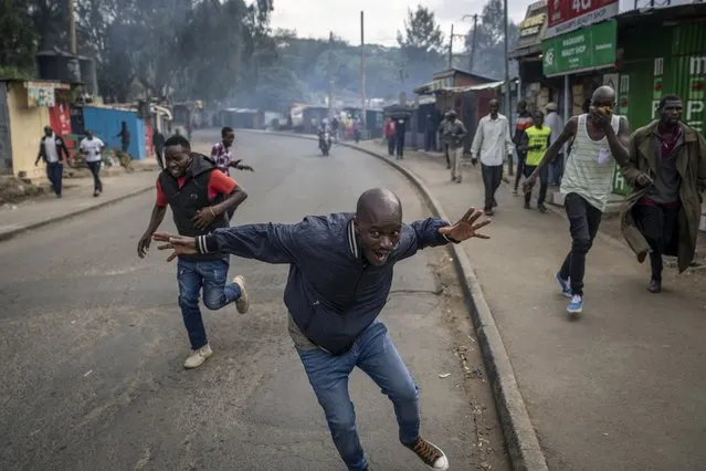 Protesters run from tear gas fired by police in the Kibera slum of Nairobi, Kenya Monday, March 20, 2023. (Photo by Ben Curtis/AP Photo)