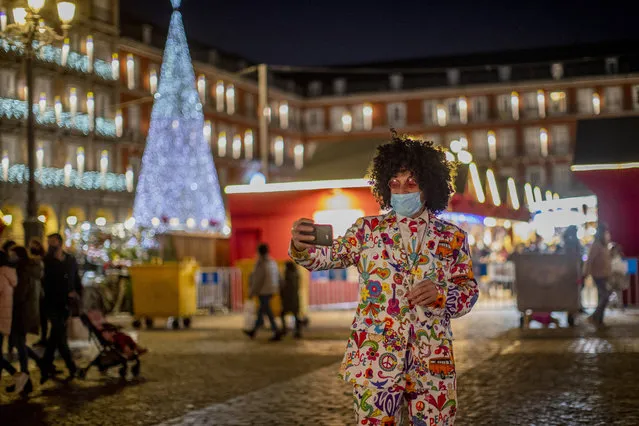 A man wearing a face mask to protect against the spread of coronavirus takes a selfie at Mayor square in downtown Madrid, Spain, Saturday, December 12, 2020. The rate of Spain's coronavirus contagion has dropped to levels not seen since the end of August, when a resurgence began in earnest, but the country's top coronavirus expert says that the situation remains of “high risk” and that the curve of contagion needs to be flattened to avoid a third wave before vaccination begins. (Photo by Manu Fernandez/AP Photo)