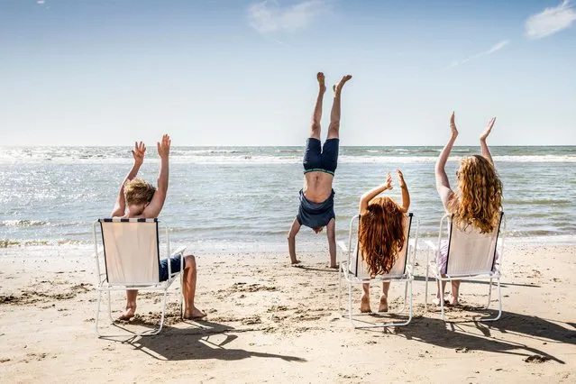 Netherlands, Zandvoort, family clapping hands for father doing a handstand on the beach. (Photo by Westend61/Getty Images)