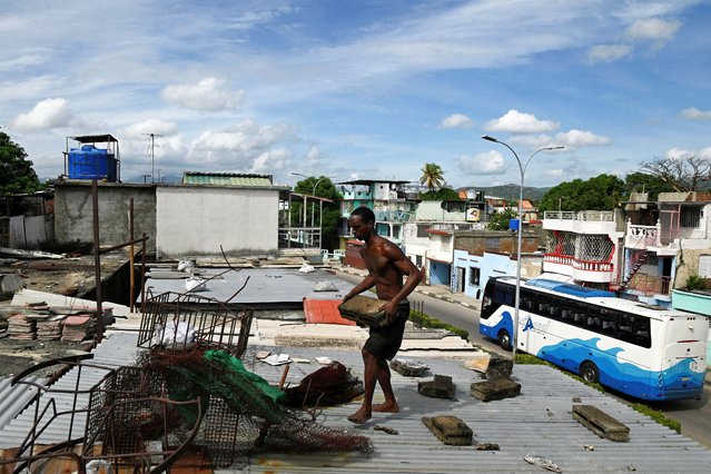 A man secures the tin roof of his house with heavy objects as he prepares for the arrival of Hurricane Melissa, in Santiago de Cuba, Cuba, on October 27, 2025. (Photo by Norlys Perez/Reuters)