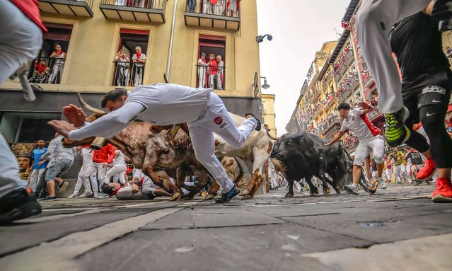Revelers run with bulls from the Jandilla ranch during the sixth day of the running of the bulls at the San FermÌn fiestas in Pamplona, Spain, Friday, July12, 2024. People test their speed and bravery by dashing with six fighting bulls through the streets of the northern Spanish city of Pamplona. (Photo by Alvaro Barrientos/AP Photo)