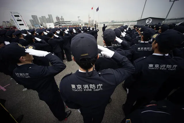 Members of firefighter salutes to the Japanese flag during the annual New Year's Fire Brigade Review in Tokyo, Tuesday, January 6, 2015. (Photo by Eugene Hoshiko/AP Photo)