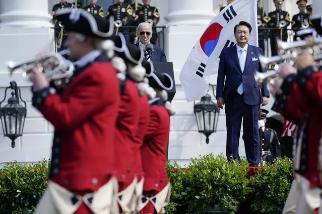 President Joe Biden and South Korea's President Yoon Suk Yeol stand on stage and watch the United States Army Old Guard Fife and Drum Corps march past, during a State Arrival Ceremony on the South Lawn of the White House Wednesday, April 26, 2023, in Washington. (Photo by Evan Vucci/AP Photo)