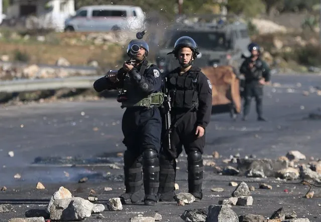 An Israeli border policeman fires a tear gas canister towards Palestinian protesters during clashes near the Jewish settlement of Bet El, near the West Bank city of Ramallah November 24, 2015. (Photo by Mohamad Torokman/Reuters)