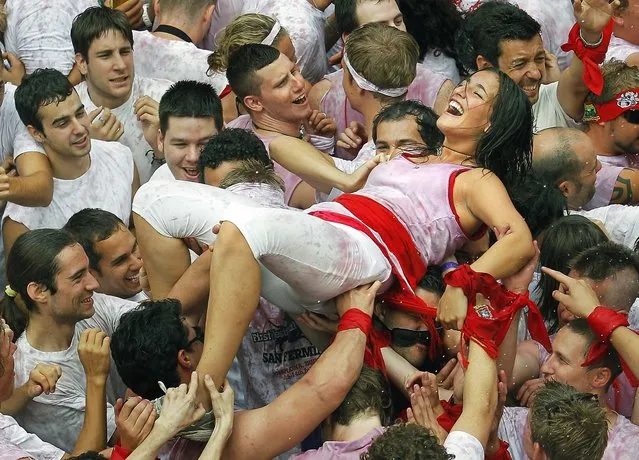 A woman is held up by revelers during the “Chupinazo”, the official opening of the 2010 San Fermin fiestas in Pamplona, Spain. The fiestas “Los San Fermines” has been held since 1591, and it attracts tens of thousands of foreign visitors each year for nine days of revelry, morning bull-runs and afternoon bullfights. (Photo by Victor R. Caivano/Associated Press)