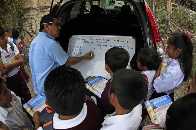 A teacher (C) from Emiliano Zapata Elementary School teaches students on the street in a nearby neighborhood in Chilpancingo, Guerrero January 8, 2015. (Photo by Jorge Dan Lopez/Reuters)