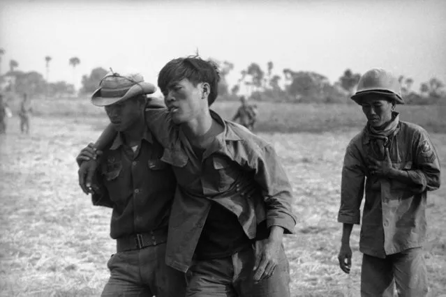 An exhausted and wounded South Vietnamese tank soldier is helped to medical station during fighting for a Viet Cong ammunition cache in Cambodia  Saturday, May 2, 1970, nine miles north of Prasaut in the northern sector of the Parrot's Beak area. The U.S. Command announced on Saturday that two American troops have been killed in ground fighting in Cambodia. (Photo by AP Photo)