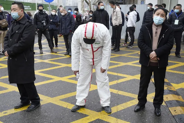 A tired worker in protective overalls bends over to stretch at the entrance of the Hubei Center for Disease Control and Prevention as the World Health Organization team makes a field visit in Wuhan in central China's Hubei province on Monday, February 1, 2021. (Photo by Ng Han Guan/AP Photo)