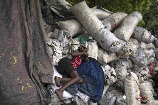 A woman rests over sacks of charcoal in Port-au-Prince, Haiti, Thursday, June 1, 2023. (Photo by Ariana Cubillos/AP Photo)